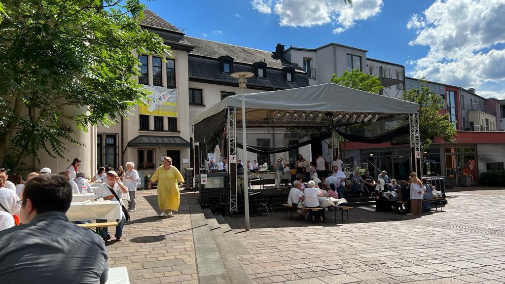 Menschen sitzen gemeinsam an Tischen beim interreligiösem Friedensmahl 2022