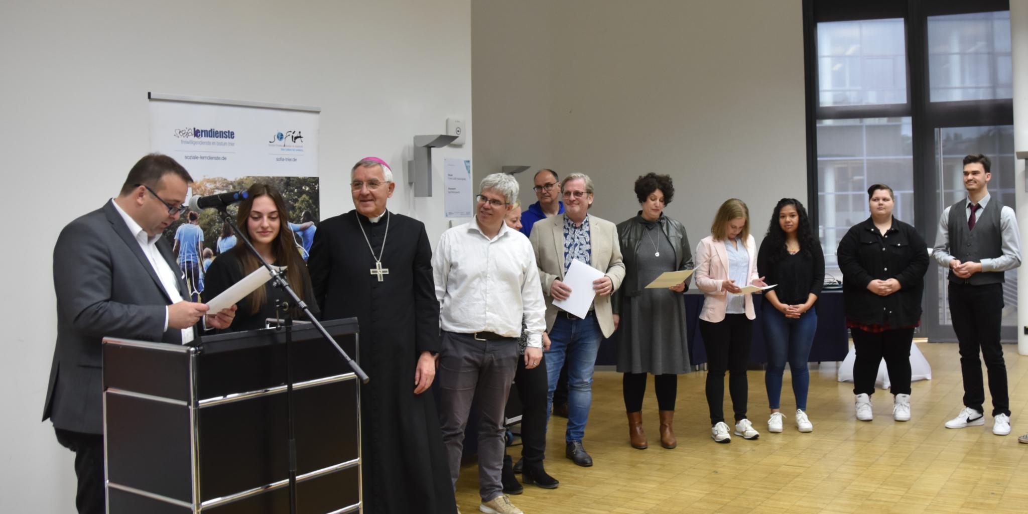 Sozialminister Jung und Weihbischof Gebert mit Freiwilligendienstleistenden bei einer Urkundenübergabe