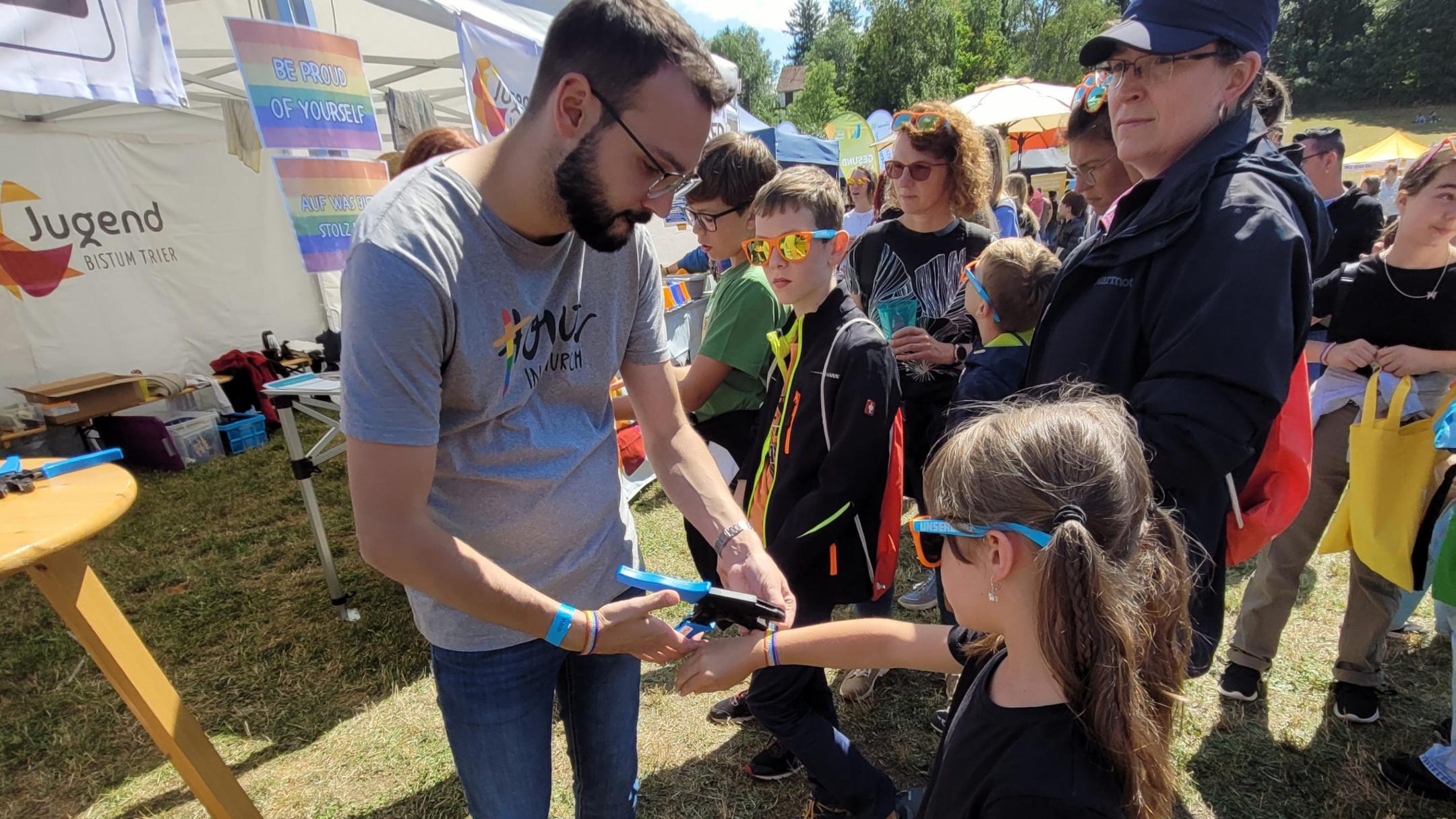 Die siebenjährige Lia, die mit ihrer Mutter vor Ort war, ließ sich stolz von Gemeindereferent Andreas Diegler ein regenbogenfarbenes Festivalbändchen umlegen.