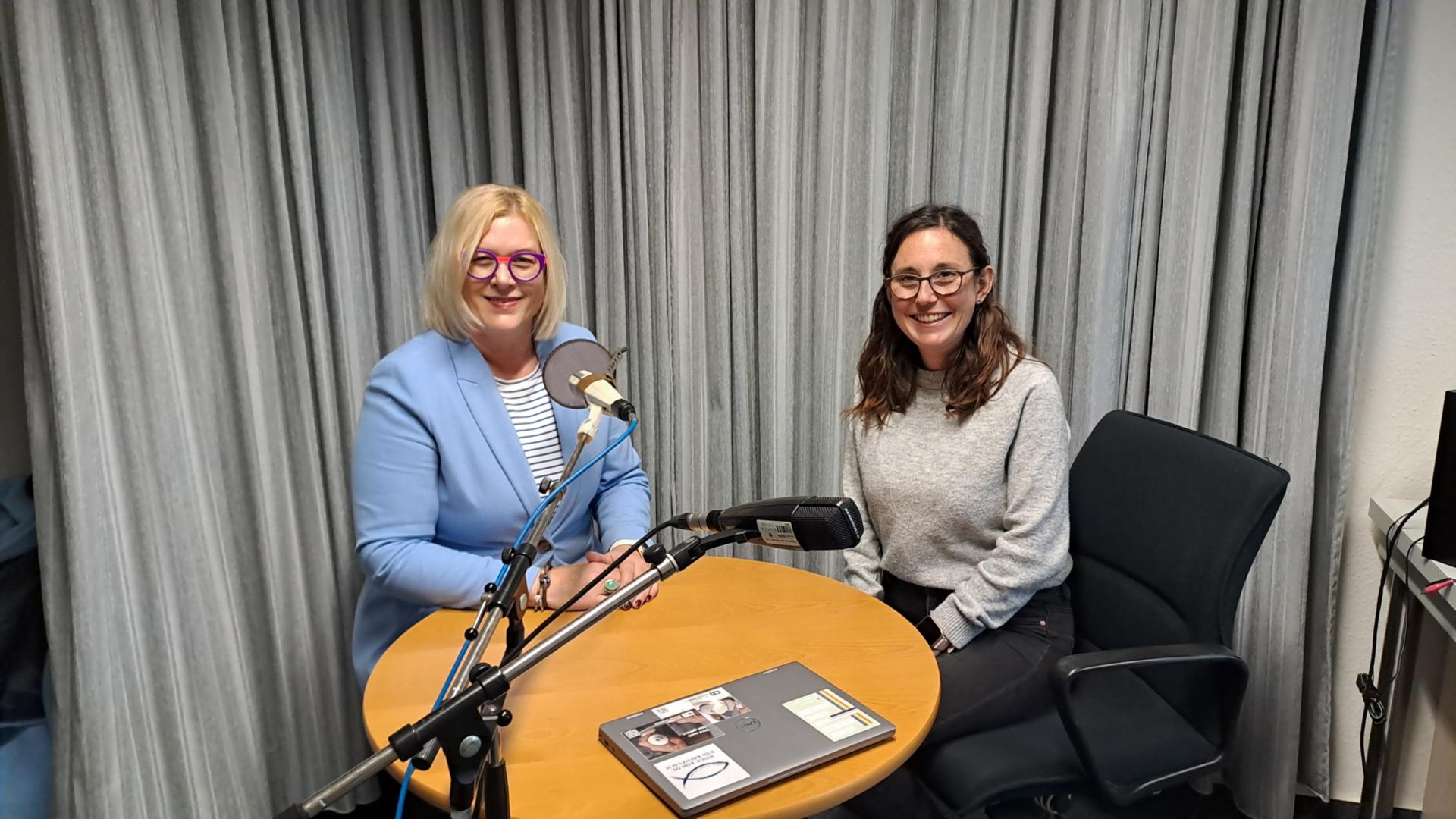 Auf dem Foto sitzen Andrea Wolter vom SkF (links) und Luisa Maurer (rechts) im Aufnahmestudio an einem Tisch und schauen in die Kamera.