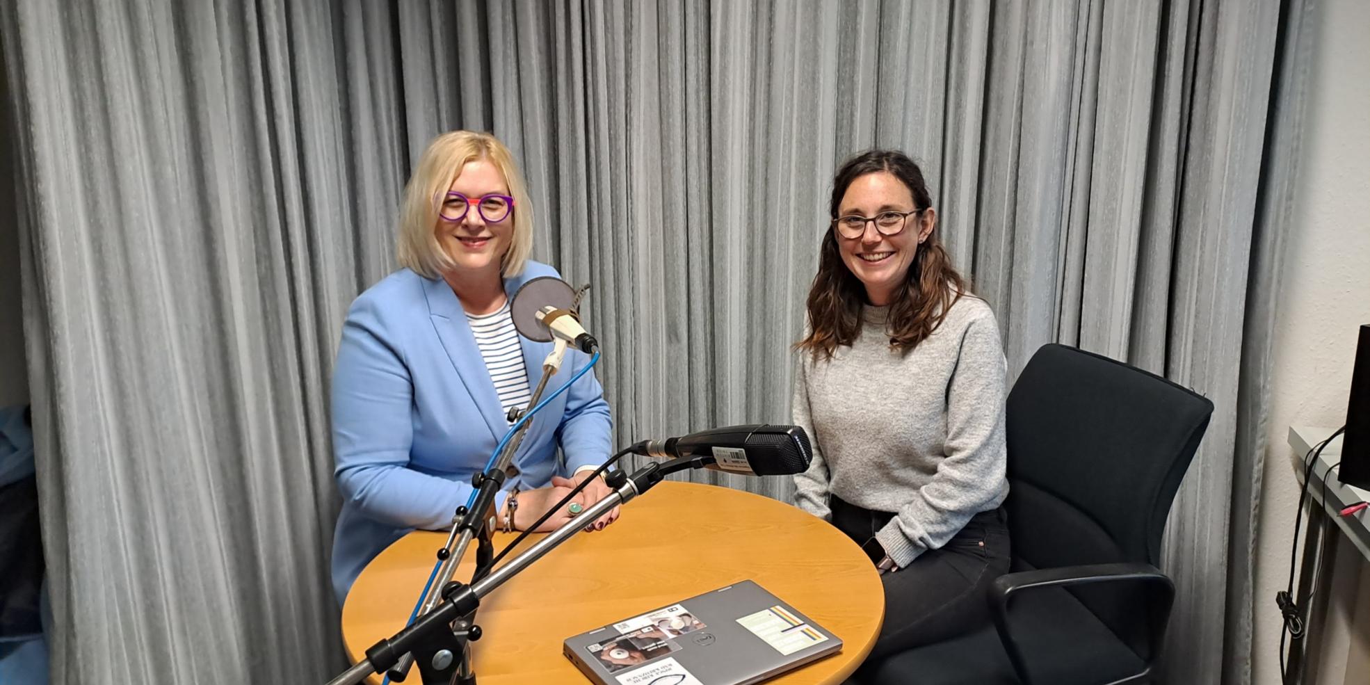 Auf dem Foto sitzen Andrea Wolter vom SkF (links) und Luisa Maurer (rechts) im Aufnahmestudio an einem Tisch und schauen in die Kamera.