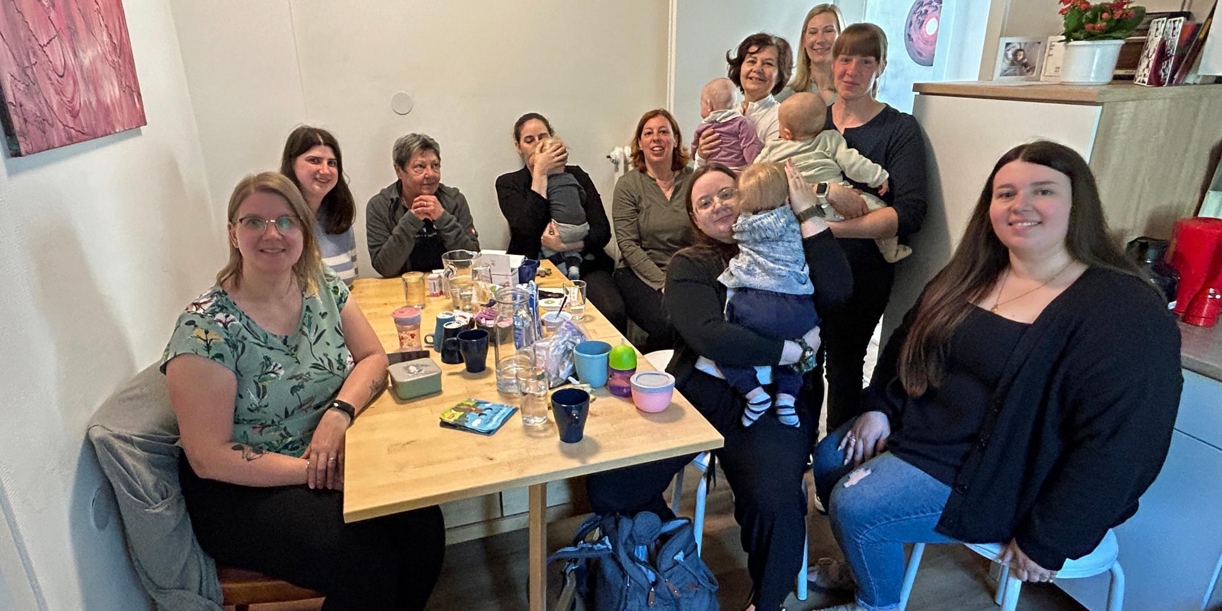 Frauen sitzen zusammen mit ihren Kindern an einem Tisch