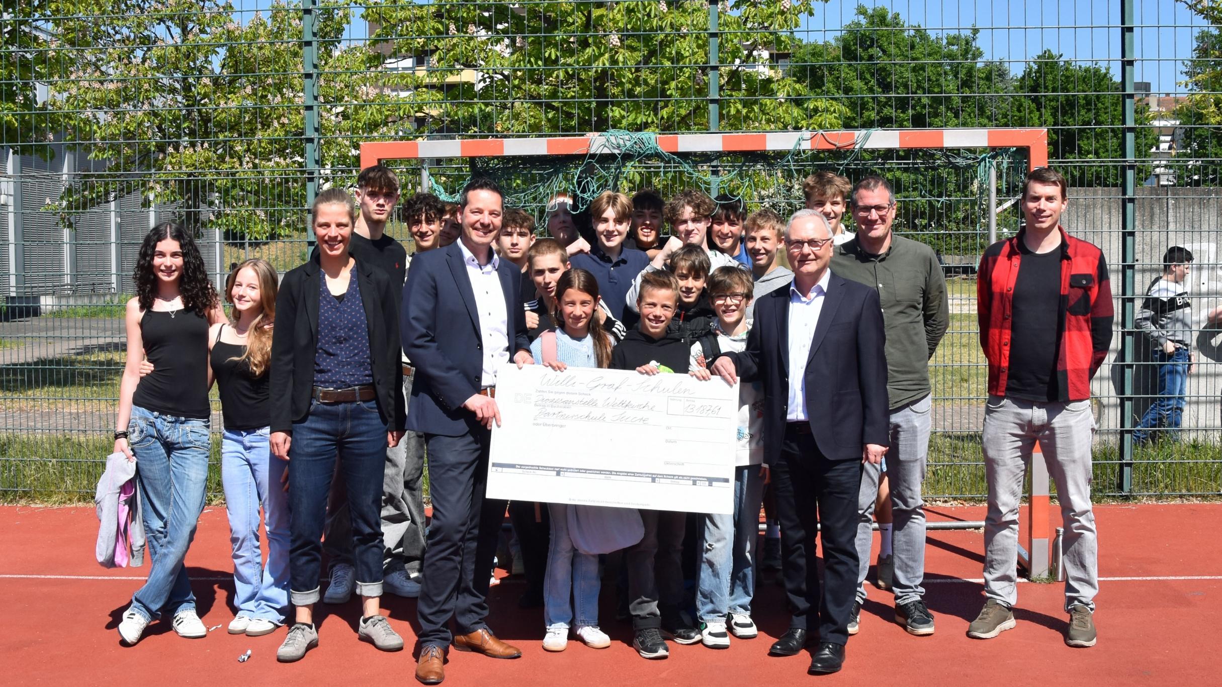 Schülerinnen und Schüler der Willi-Graf-Schulen und ihre Schulleiter Stefan Kilz und Stephan Arnold überreichen einen Scheck über 13.000 Euro an Thorsten Hoffmann und Katharina Nilles von der Diözesanstelle Weltkirche.