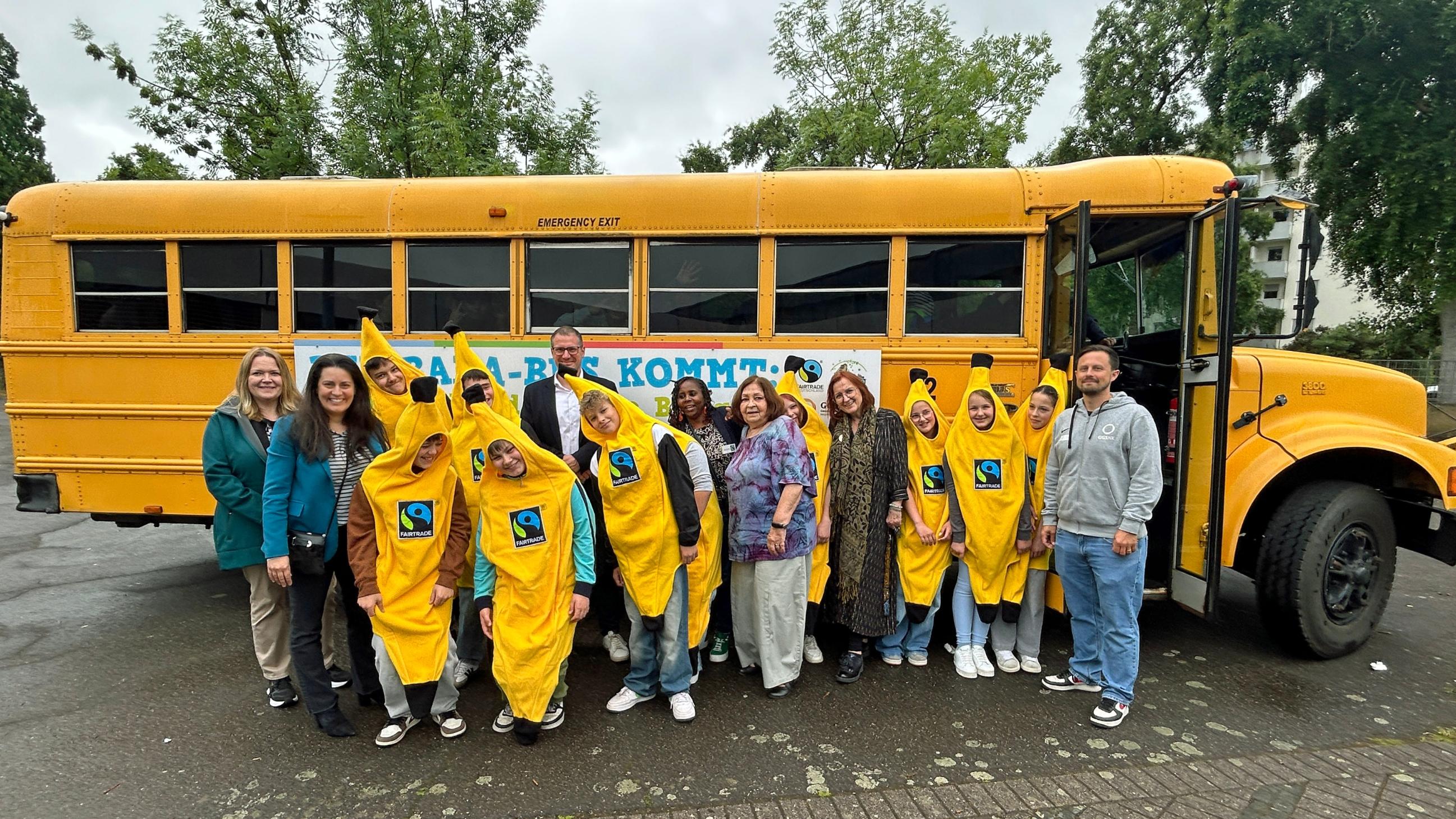 Vor dem Banabus feiern Schülerinnen und Schüler gemeinsam mit Schulleiter Stephan Arnold, Regionalverbandsdirektorin Carolin Lehberger, Bildungsdezernentin Kerstin Theobald und Winnie Mbindyo von Fairtrade Deutschland das zehnte Jubiläum der Willi-Graf-Realschule als Fairtrade-School.