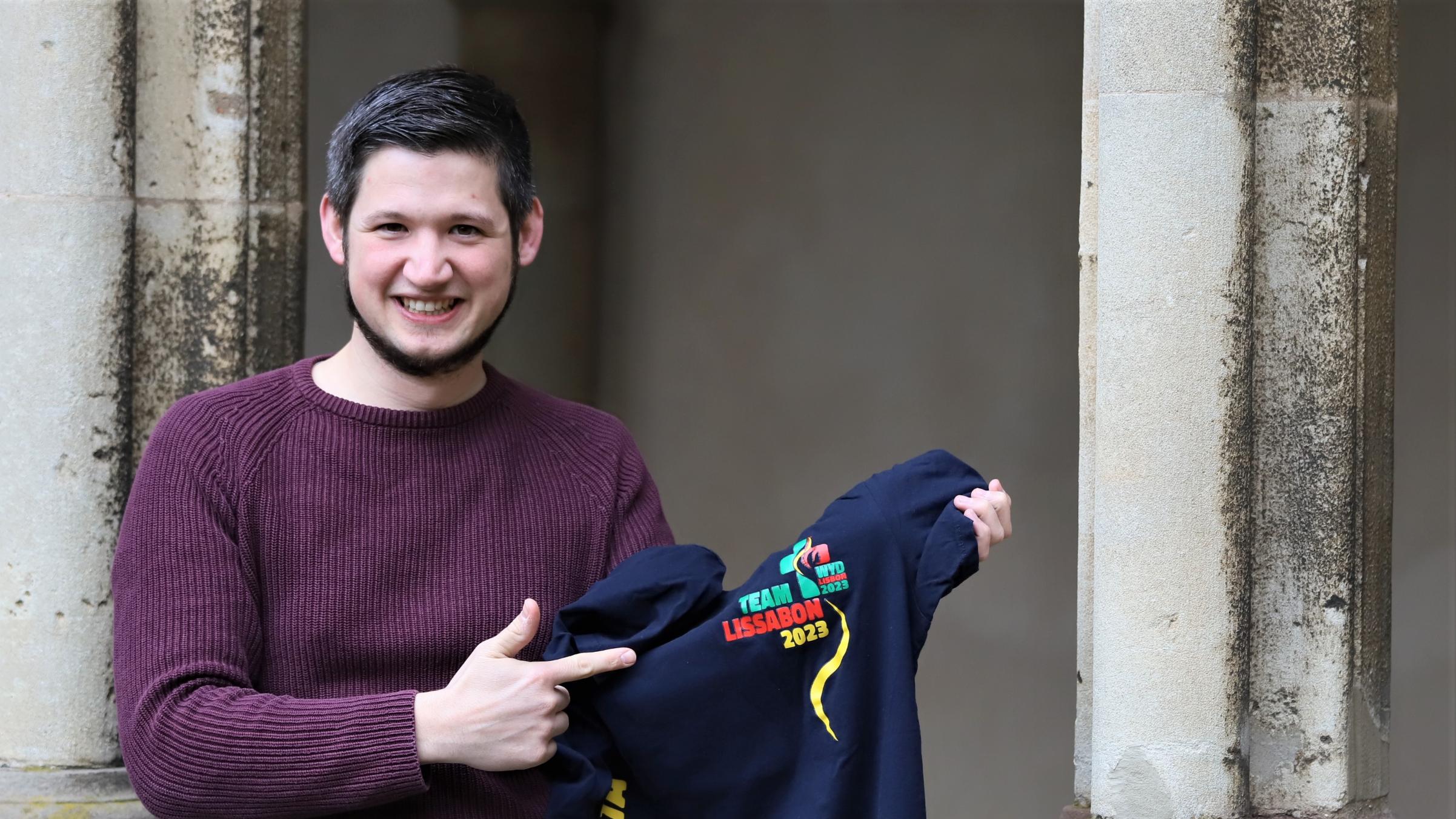 Benedikt Welter von der Abteilung Jugend im Bistum Trier zeigt ein T-Shirt vom Weltjugendtag 2023 in Lissabon