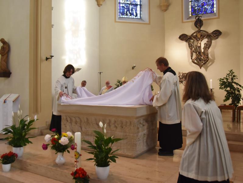 Messdiener räumen den geschmückten Altar ab.