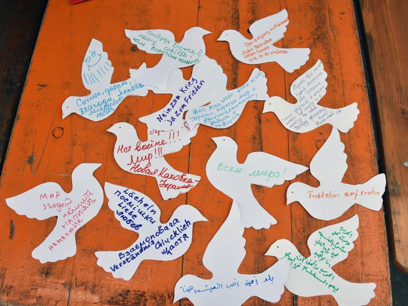 In unterschiedlichen Sprachen haben Menschen ihre Wünsche auf die Friedenstauben geschrieben.