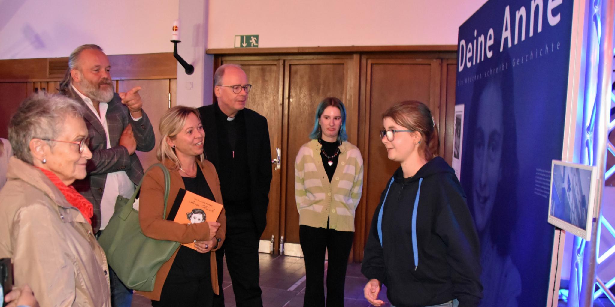 Eine Jugendliche führt Besucher - darunter Staatssekretärin Jessica Heide und Bischof Ackermann - durch die Ausstellung.