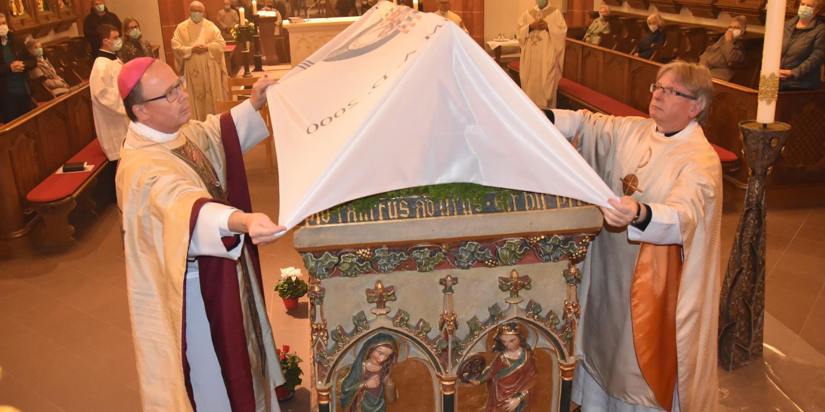 Bischof Stephan Ackermann und Pastor Klaus Leist verhüllen den Schrein des heiligen Wendelin.