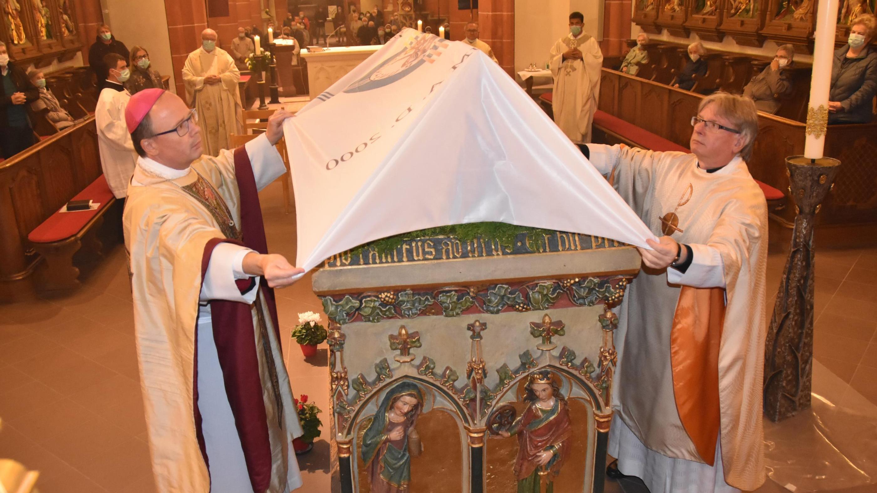 Bischof Stephan Ackermann und Pastor Klaus Leist verhüllen den Schrein des heiligen Wendelin.