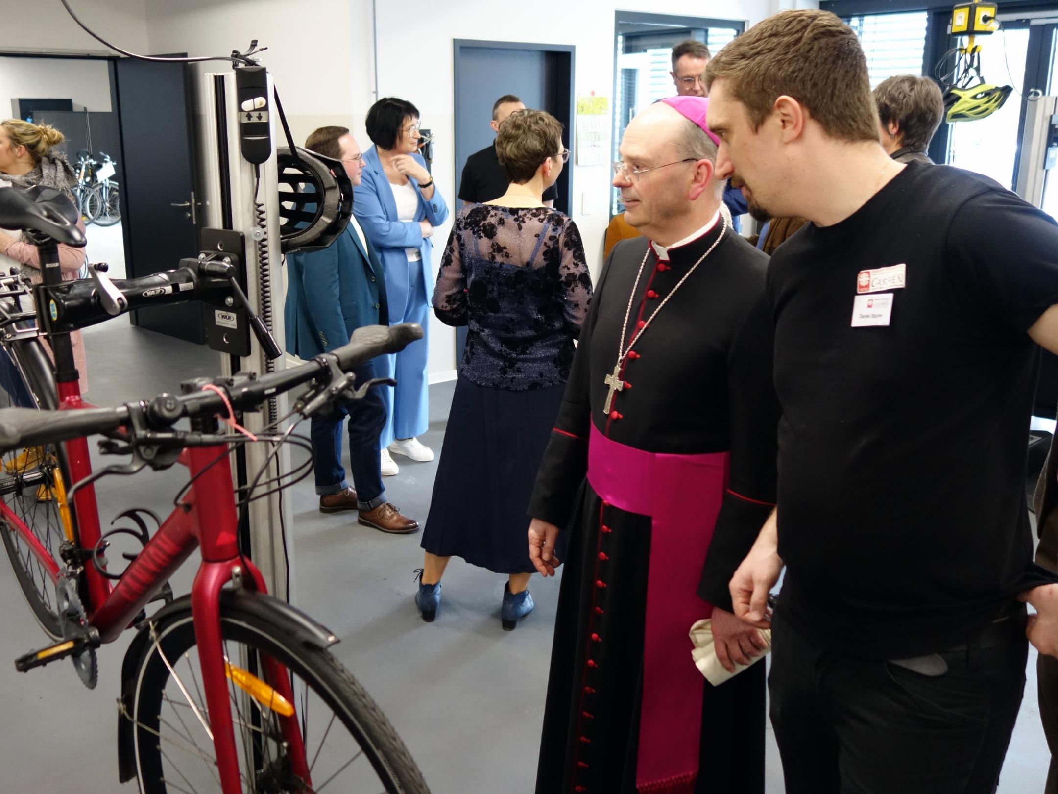 Weibischof Brahm schaut sich die Fahrradwerkstatt an und lässt sich beraten.