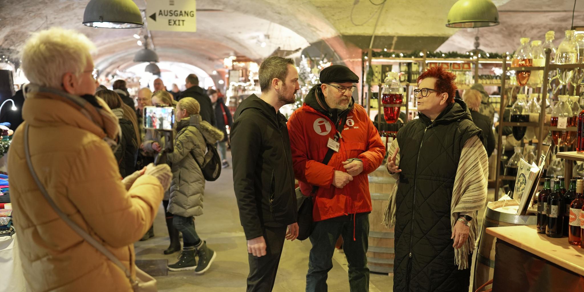 Gabriele Centurioni (rechts) und Tobias Schmitt treffen sich auf dem Wein-Nachts-Markt mit Gästeführer Günter Hauenstein (Zweiter von rechts). Monika Hochscheid (links) zeichnet das Video auf.