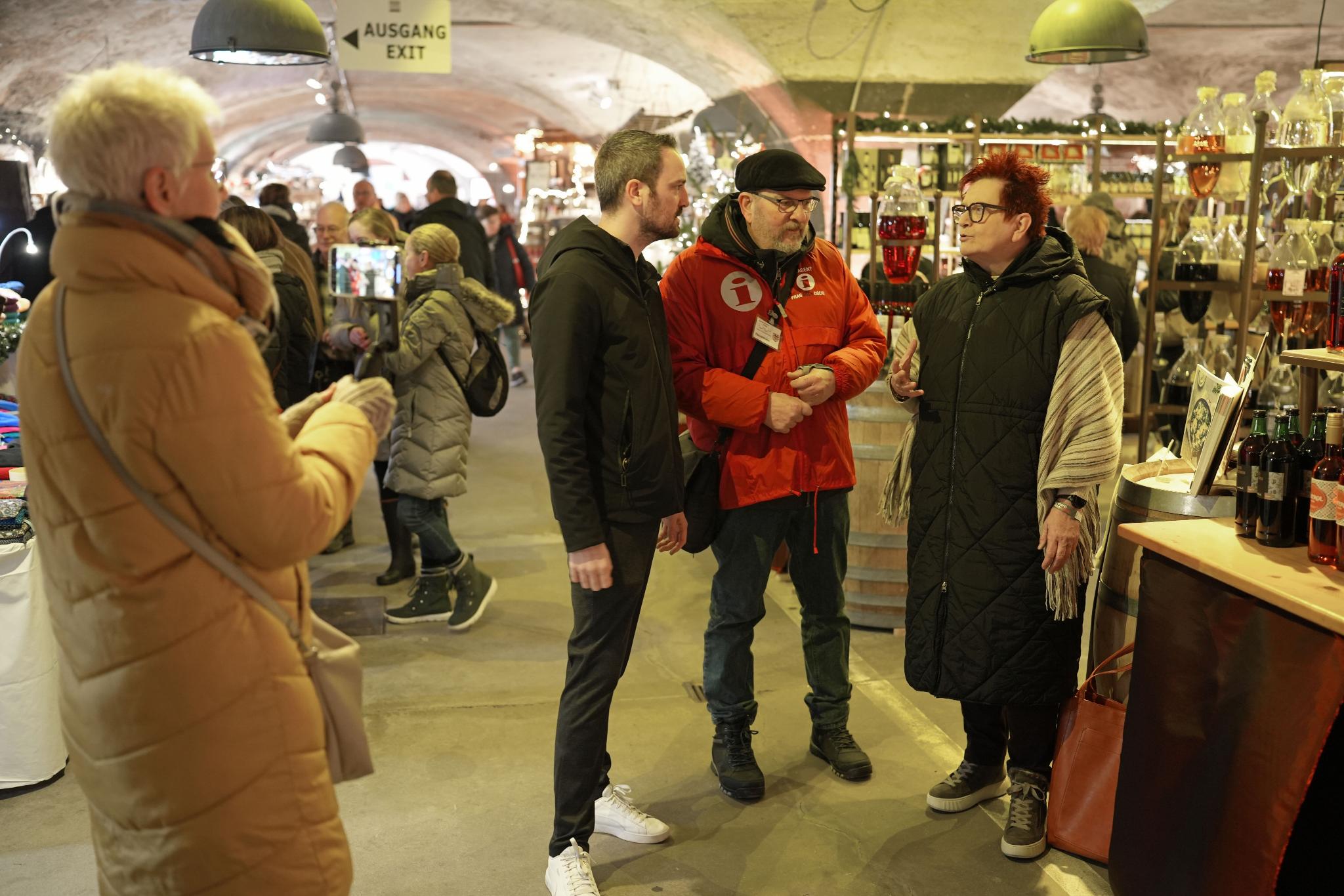 Gabriele Centurioni (rechts) und Tobias Schmitt treffen sich auf dem Wein-Nachts-Markt mit Gästeführer Günter Hauenstein (Zweiter von rechts). Monika Hochscheid (links) zeichnet das Video auf.