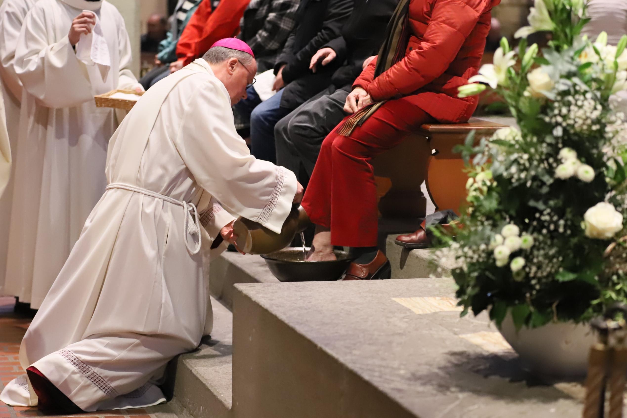 Bischof Ackermann bei der Fußwaschung, an Frauen und Männer aus der St. Jakobus-Bruderschaft und den Besucherdiensten von Dom und Bistum