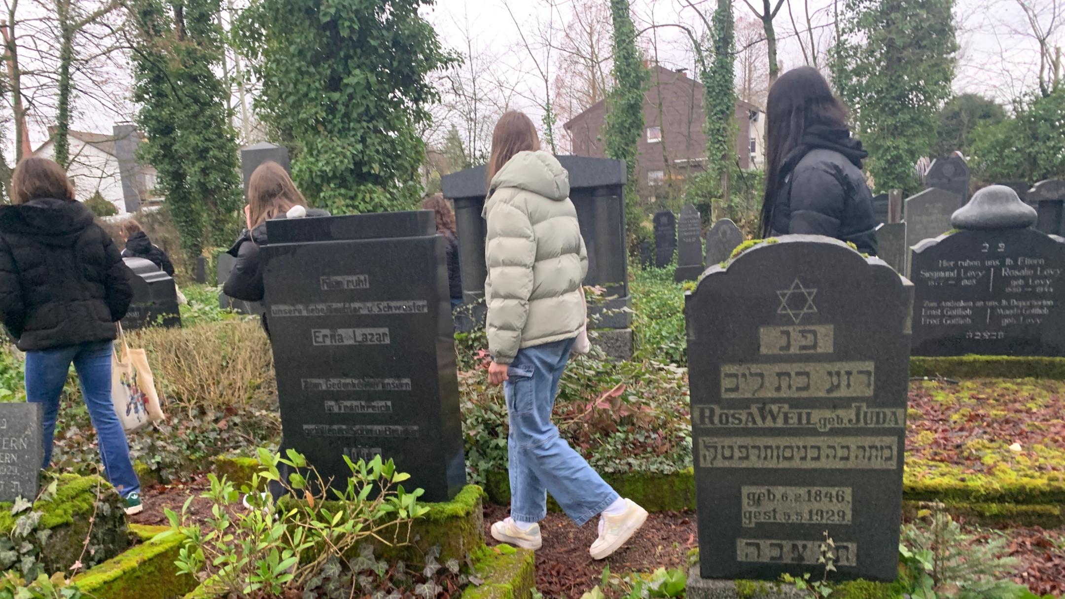 Schülerinnen und Schüler legen Steine auf jüdischen Gräbern in Saarlouis nieder.