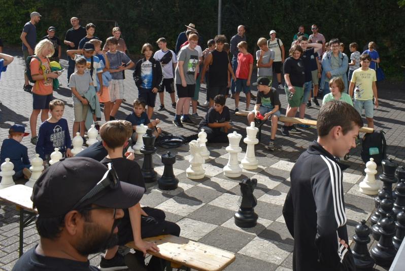 Viele Jungs stehen um ein großes Schachbrett herum.