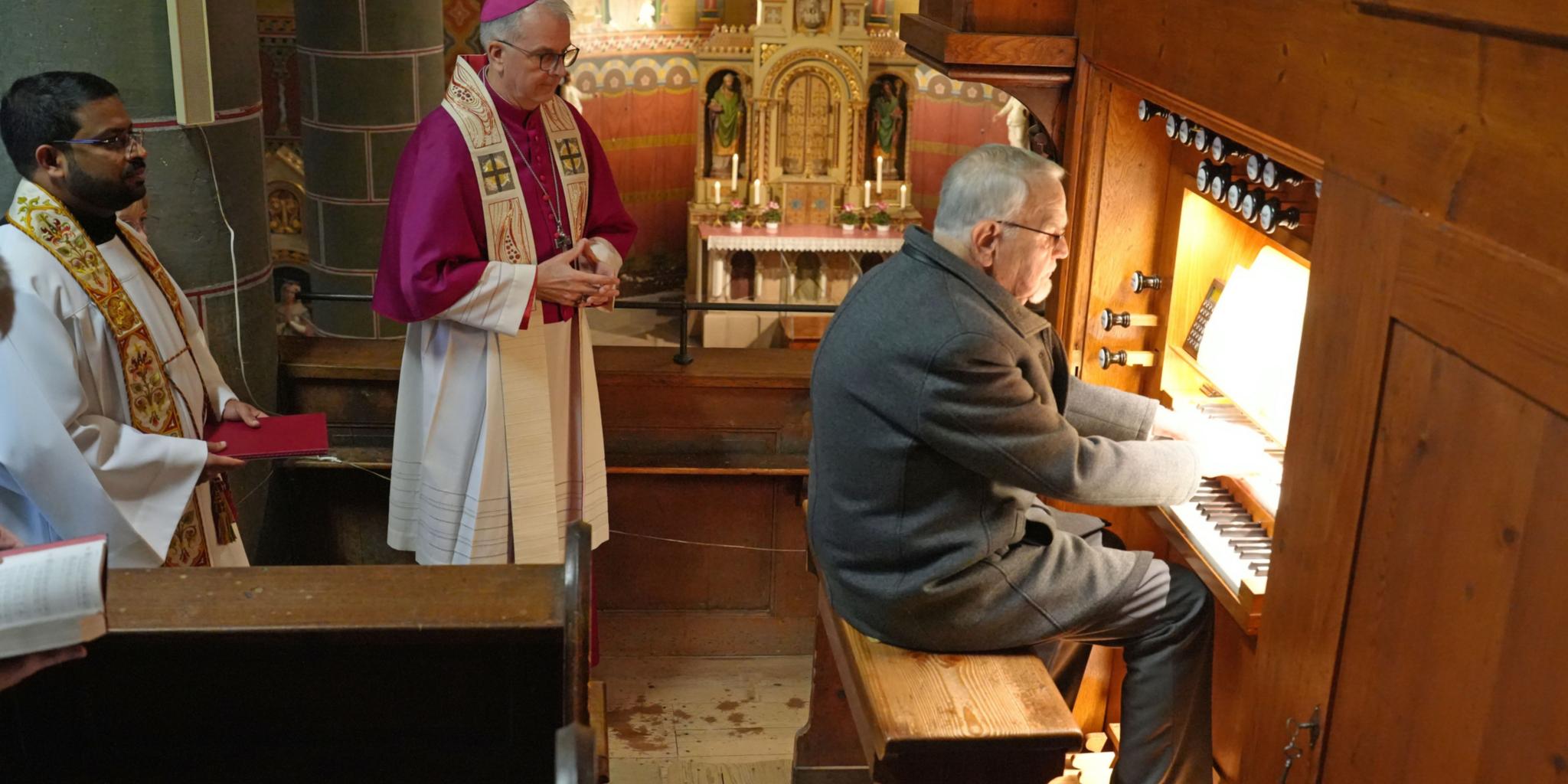 Organist Winfried Hansel spielt zum Auftakt das kleine 'Präludium C-Dur' von Bach. Dahinter stehend Weihbischof Peters und Pfarrer Antony