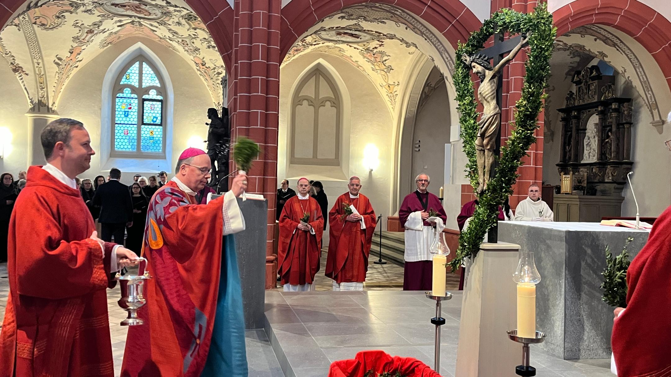 Bischof Ackermann segnet in der Bürgerkirche St. Gangolf die Palmzweige.