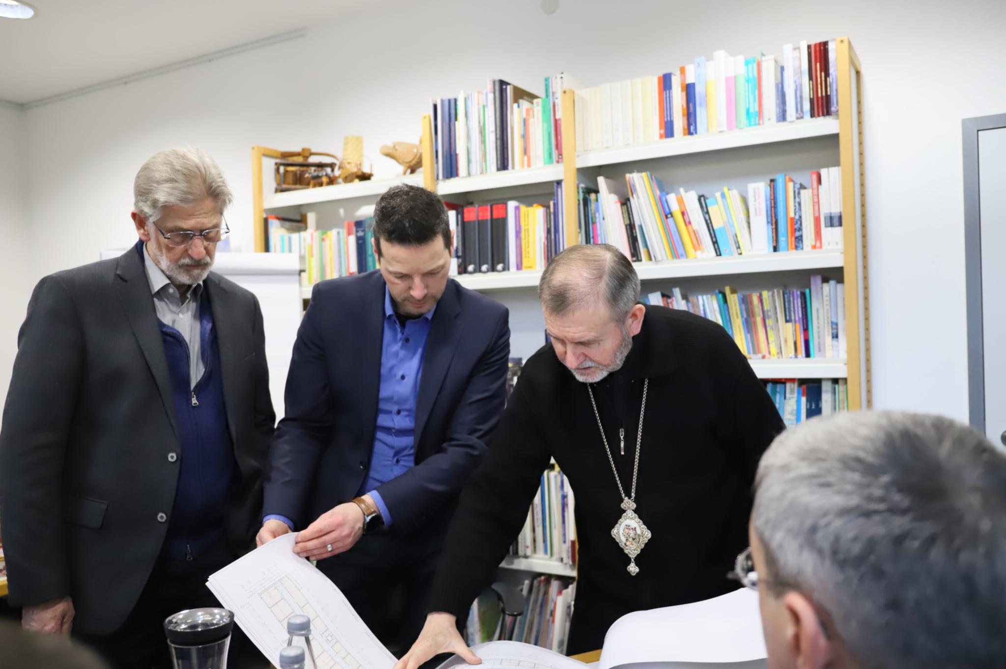 Bischof Dmytro Hryhorak zeigt Dr. Thorsten Hoffmann und Ludwig Kuhn die Pläne für ein Krankenhaus in der Ukraine