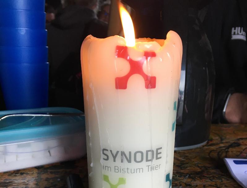 Eine brennende Kerze mit der Aufschrift 'Synode'.