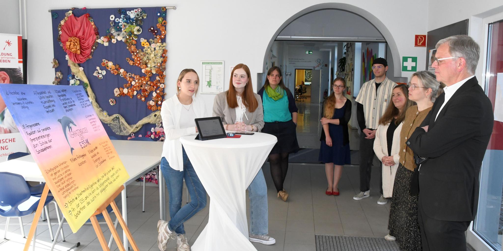 Vivien Schneider und Anna Walle (v. l.) stellen Generalvikar von Plettenberg den Verhaltenskodex der Schule vor.