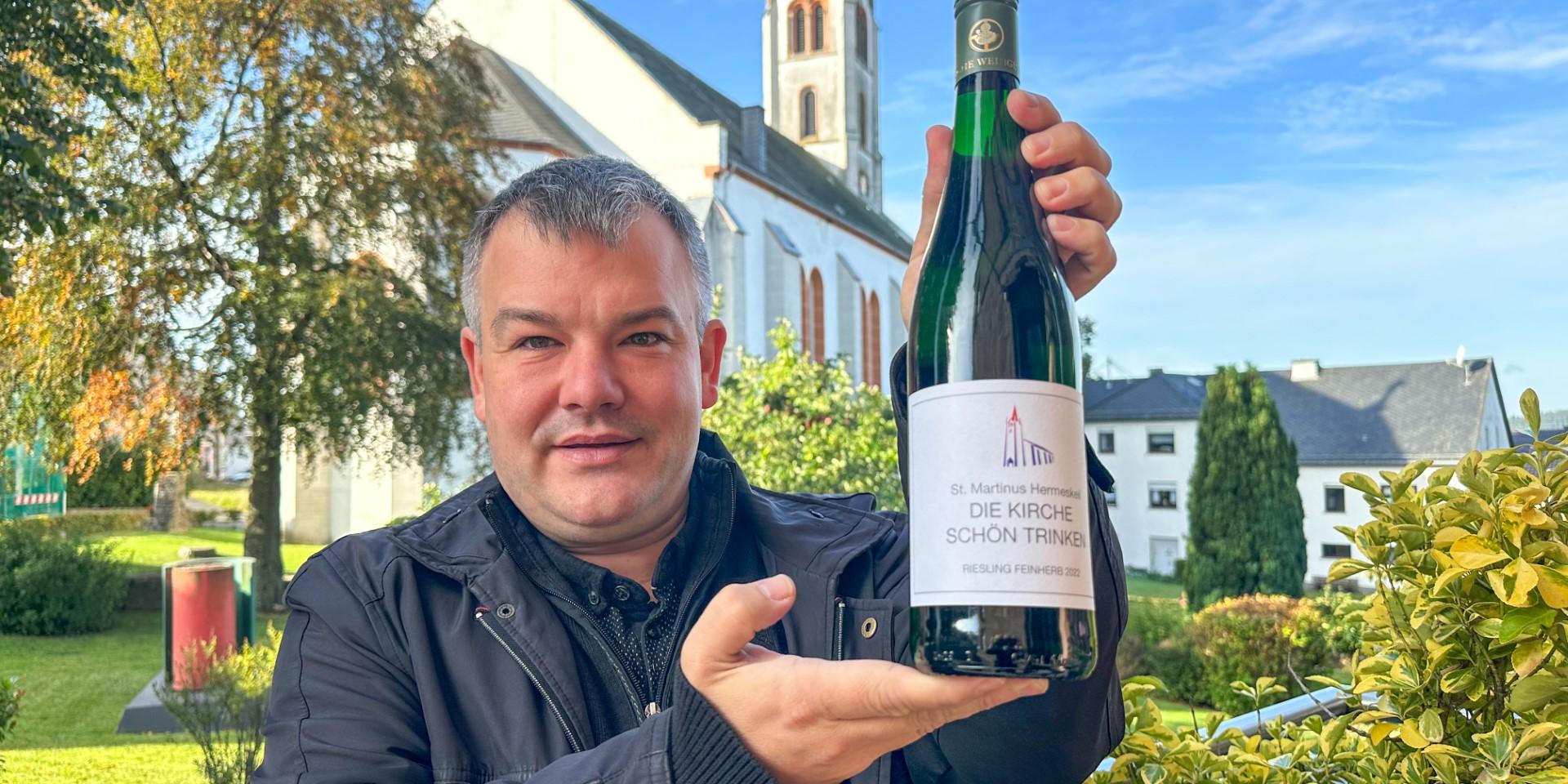 Dekan Christian Heinz präsentiert vor der St. Martinus-Kirche eine der 5000 Flaschen des Charity-Weins.