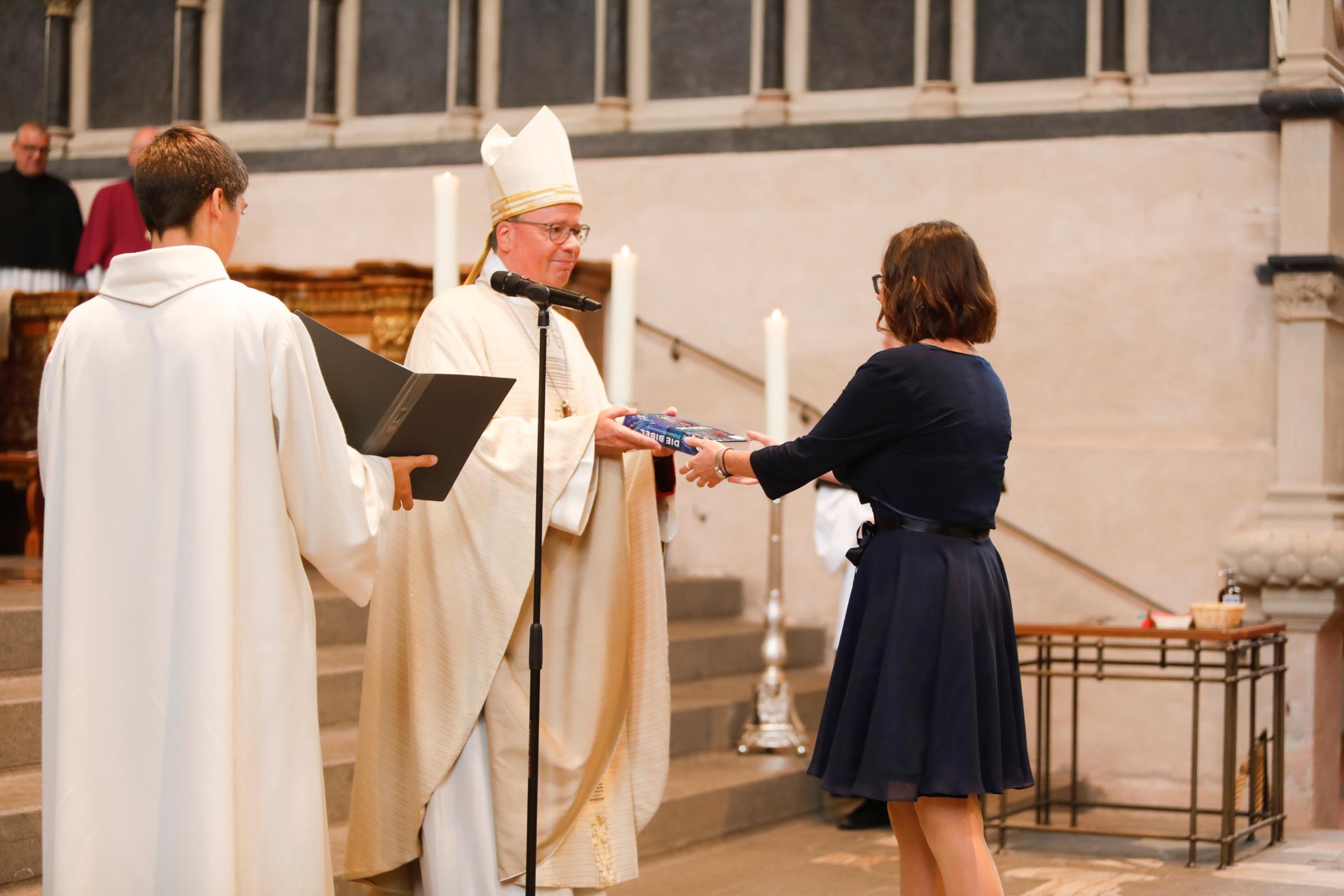 Bischof Ackermann überreicht Luisa Maurer eine Bibel.