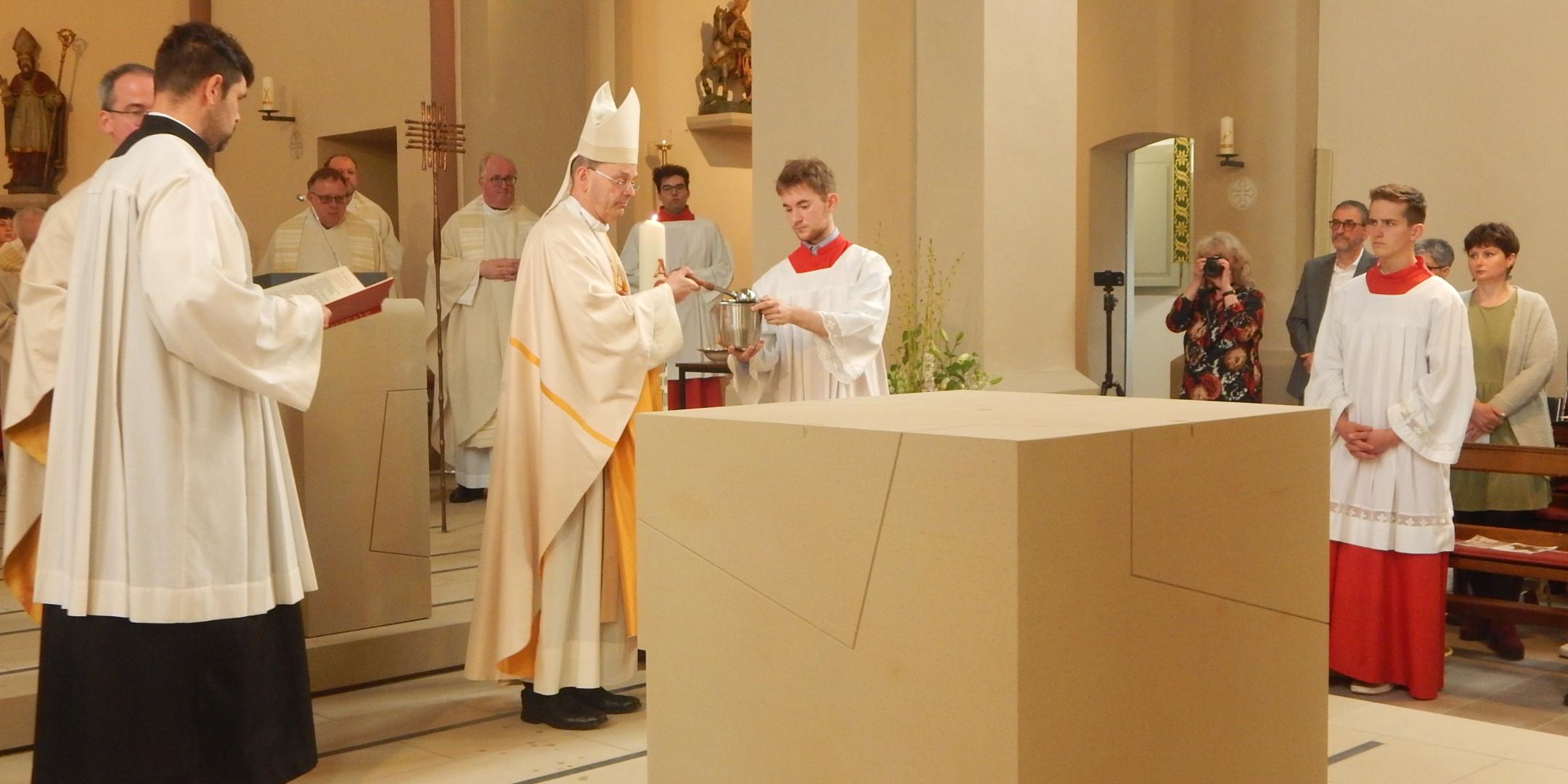 Weihbischof Robert Brahm besprengt den Altar mit Weihwasser