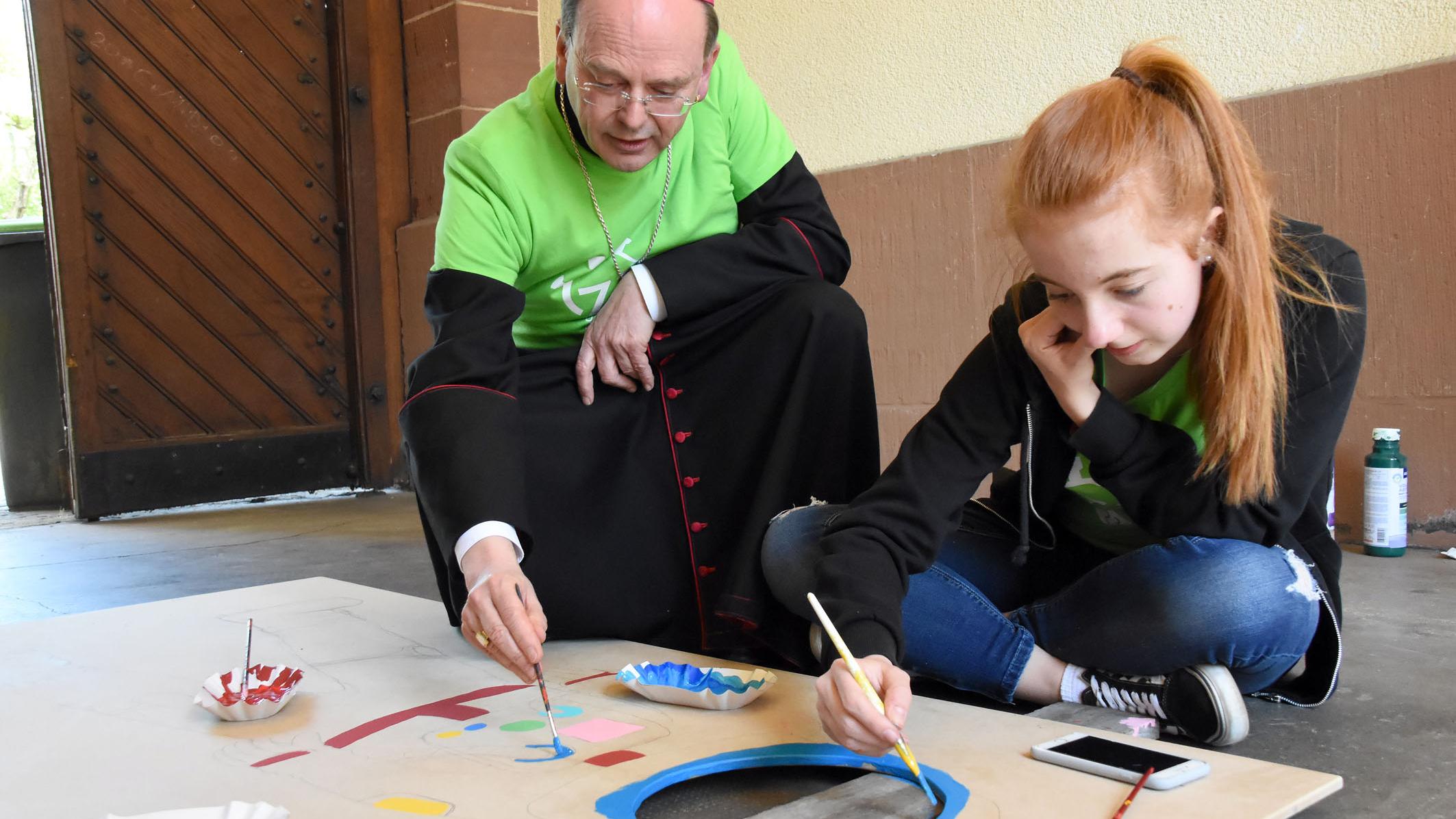 Weihbischof Robert Brahm hat sich bei seinem Besuch selbst einen Pinsel geschnappt und den Jugendlichen geholfen. (Foto: Hans Georg Schneider)