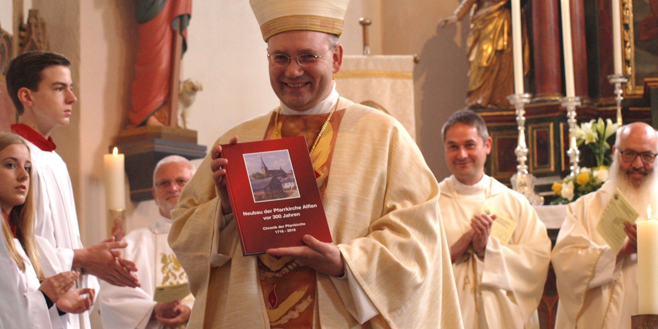 Weihbischof Helmut Dieser erhält am Ende des Gottesdienstes die neuerschienene Chronik zur Alfler Pfarrkirche.