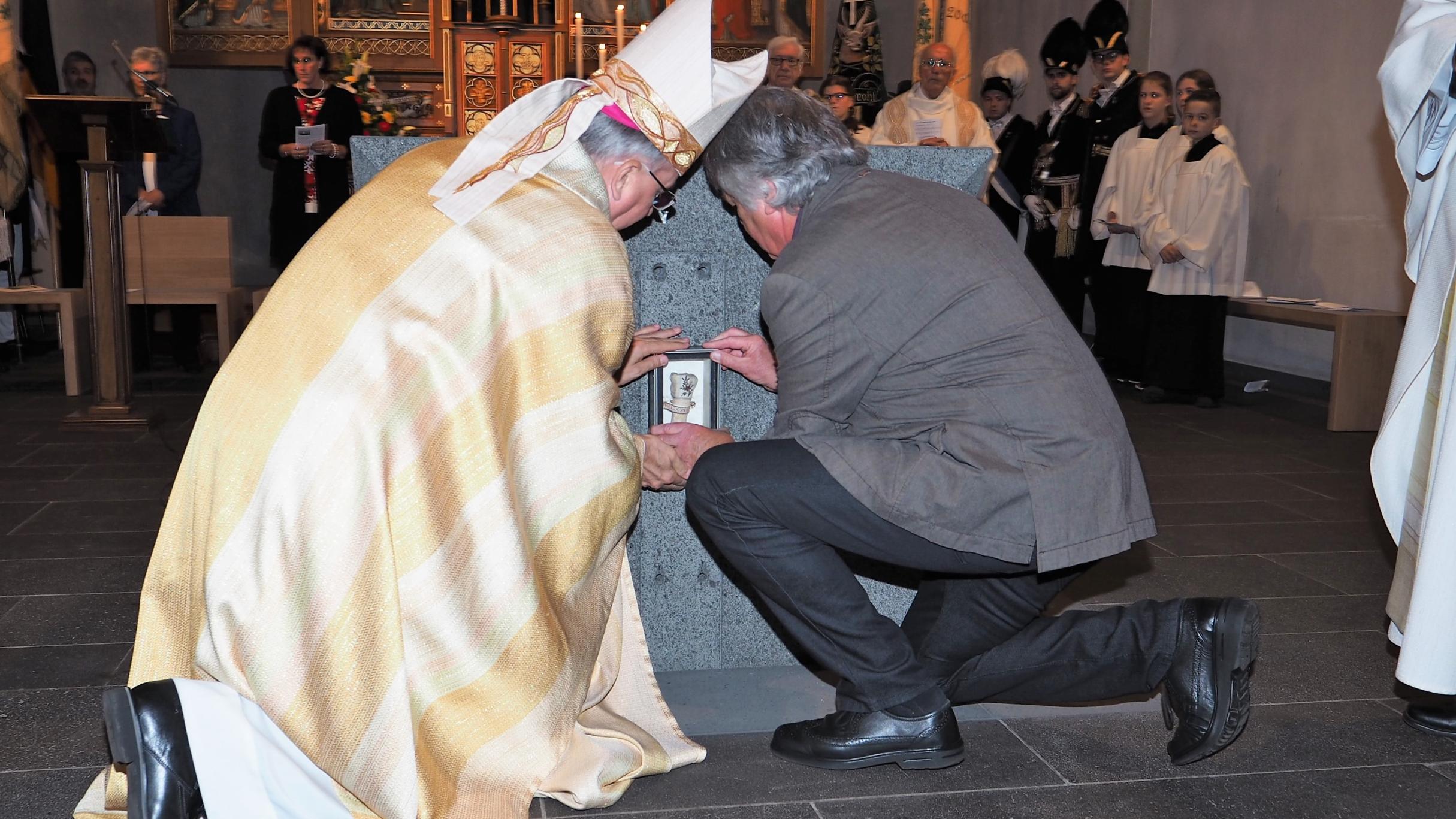 Weihbischof Jörg Michael Peters (links) und der Bildhauer Hans Rams setzten die Reliquie in den neuen Altar ein.