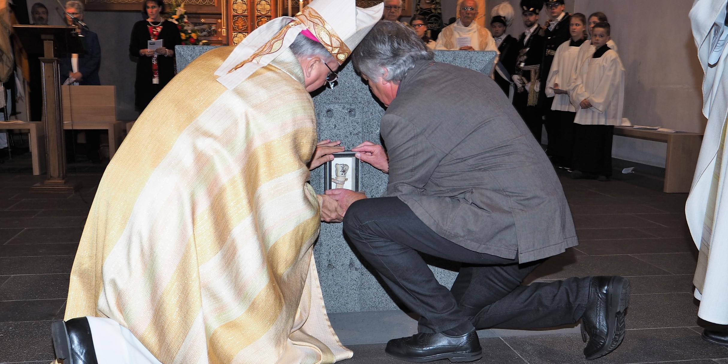 Weihbischof Jörg Michael Peters (links) und der Bildhauer Hans Rams setzten die Reliquie in den neuen Altar ein.
