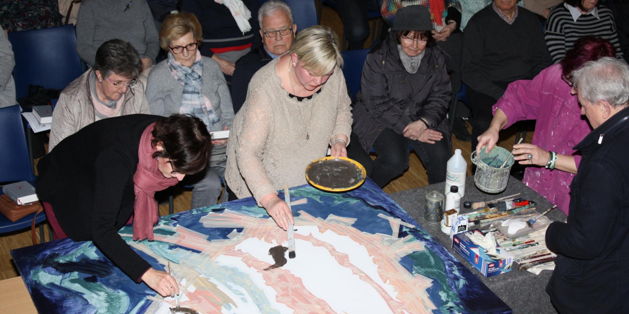 Gemeinsam mit den Gottesdienstbesuchern wird mit Asche ein herzförmiges Bild gestaltet.