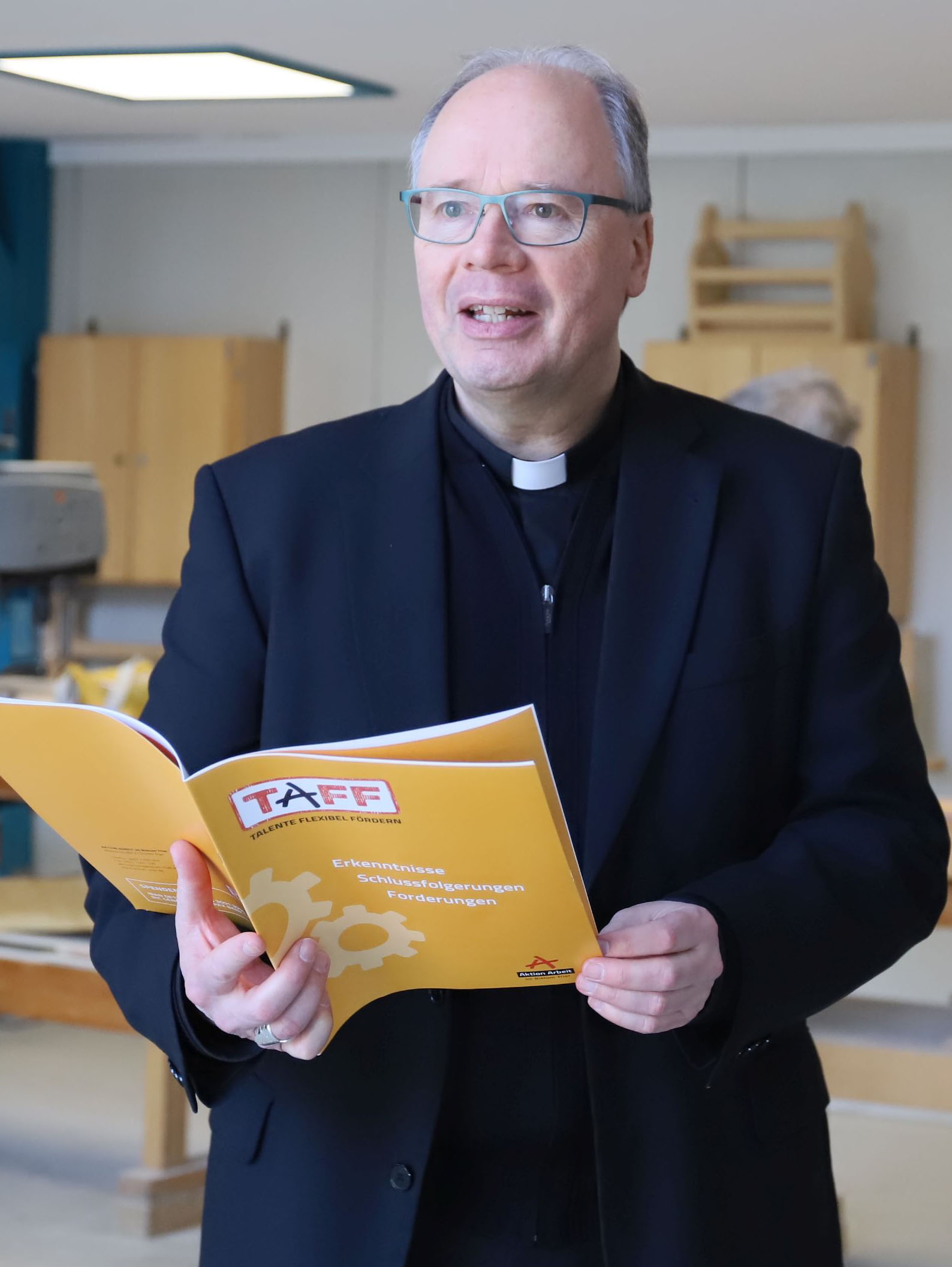 Bischof Ackermann wirft einen Blick in die jüngst veröffentlichte TAFF-Bröschüre. Foto: Inge Hülpes/Bistum Trier
