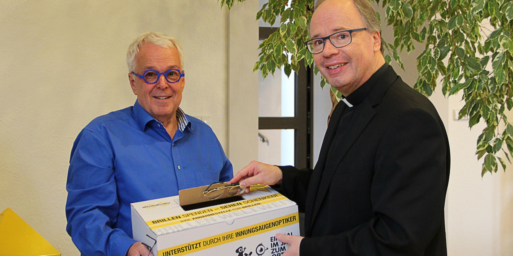 Carlo Wagner nimmt die erste Spende für die Brillenbox in der CAféteria des BGV entgegen: Ein altes Modell von Bischof Stephan Ackermann. Insgesamt fünf alte Brillen hat er gespendet.