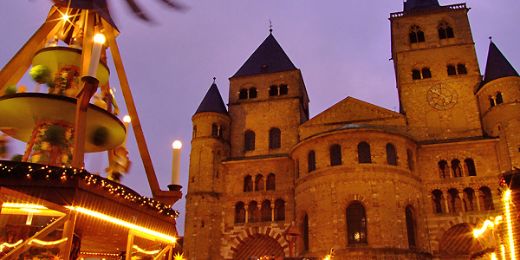 Auf dem diesjährigen Titelbild des Adventskalenders, ist die Weihnachtspyramide auf dem Domfreihof und im Hintergrund die Hohe Domkirche zu Trier in weihnachtlicher Abendstimmung zu sehen.