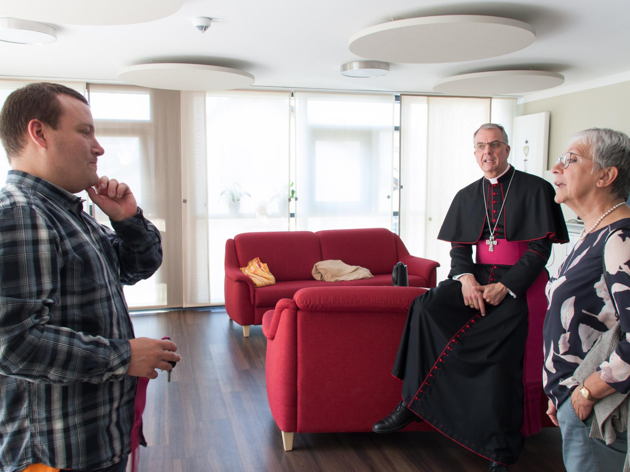 Daniel (links) zeigt Weihbischof Peters und Claudia Horbach, Bereichsleiterin Wohnen, die Wohnküche.