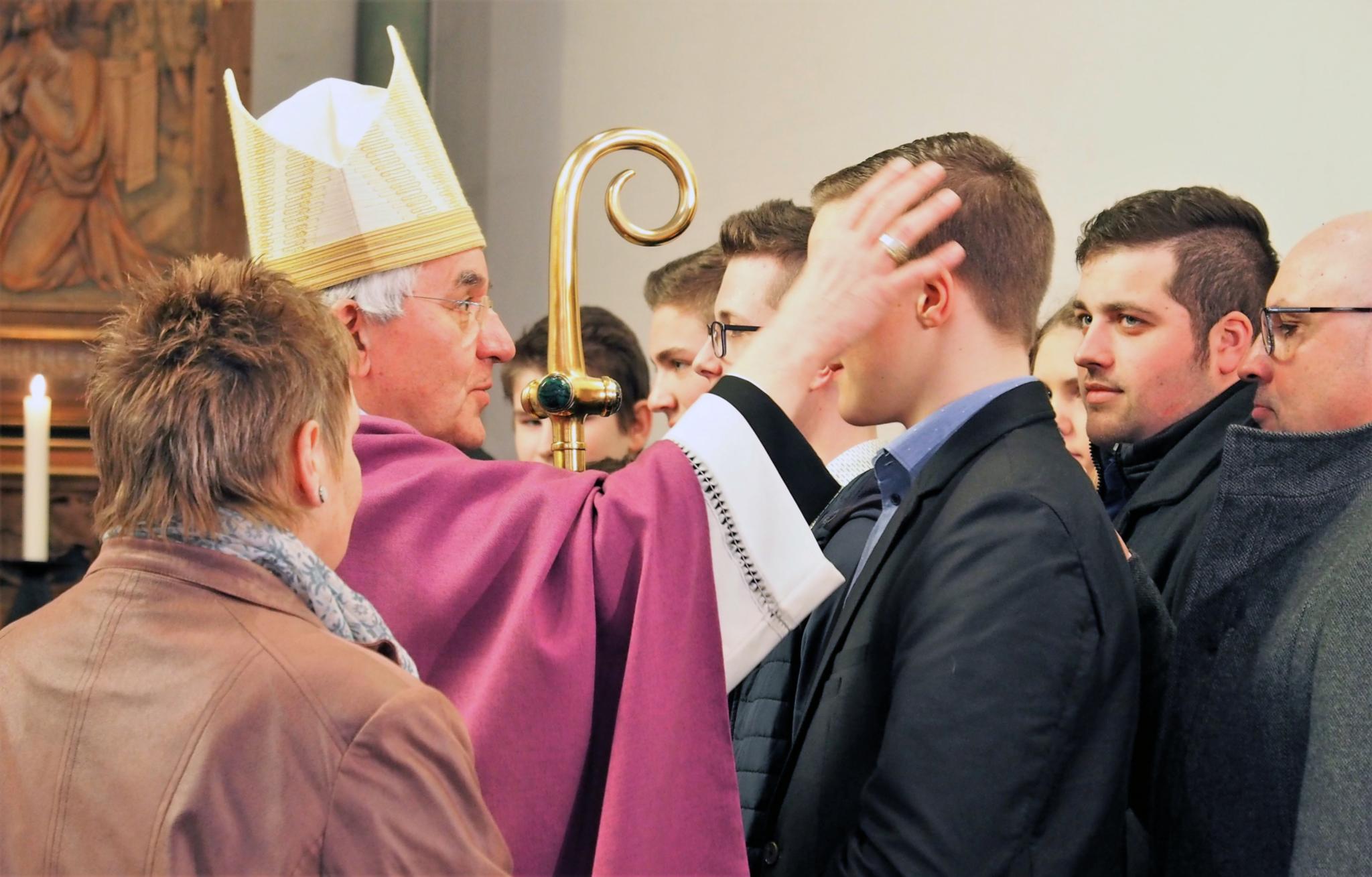 Weihbischof Franz Josef Gebert spendet den jungen Menschen in der Pfarrkirche St. Hubertus in Großkampenberg das Sakrament der Firmung mit einem Kreuzzeichen auf der Stirn.