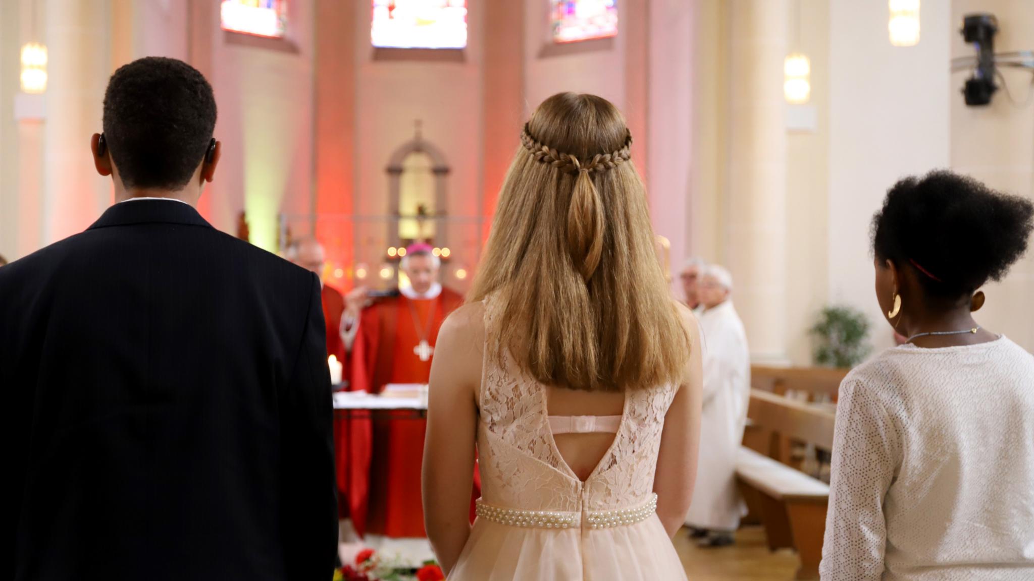 1 Junge und zwei Mädchen stehen mit dem Rücken zum Fotografen und schauen auf den Weihbischof