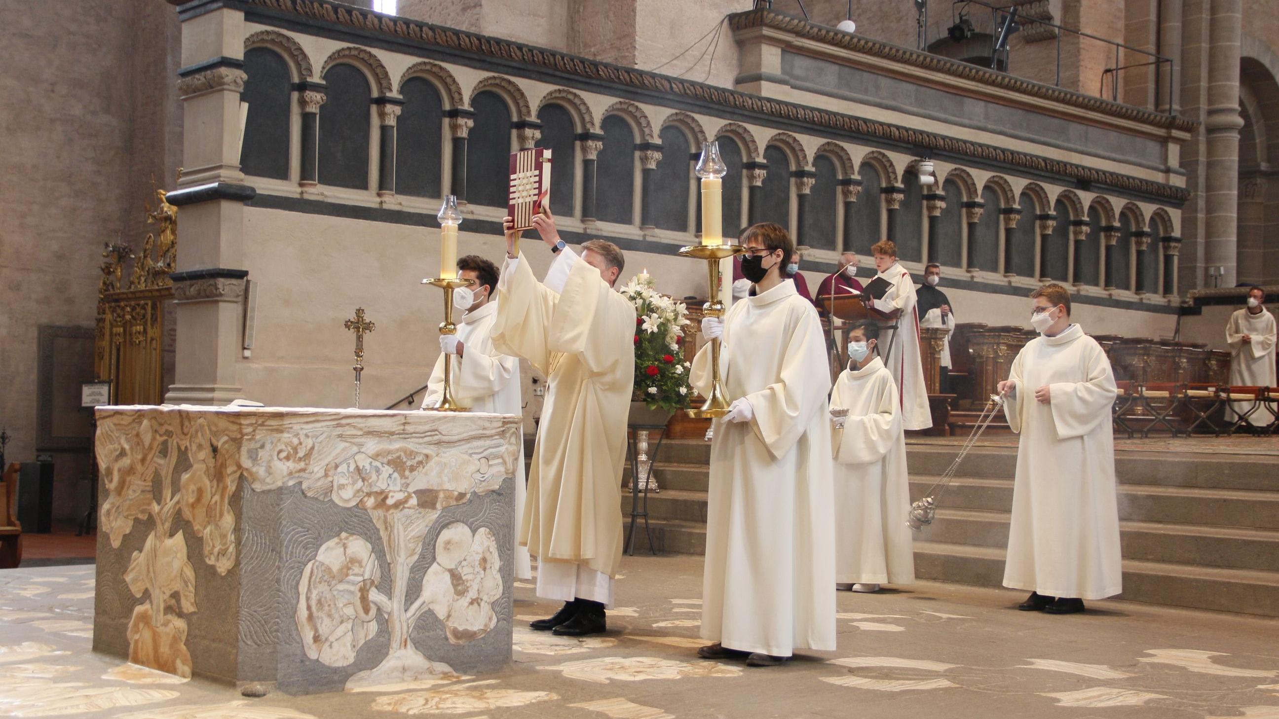 Seit vielen Jahrhunderten wird im Trierer Dom Gottesdienst gefeiert. Diakon Ulrich Weinand zeigt der Gottesdienstgemeinde das Evangeliar, bevor er das Evangelium verkündet.