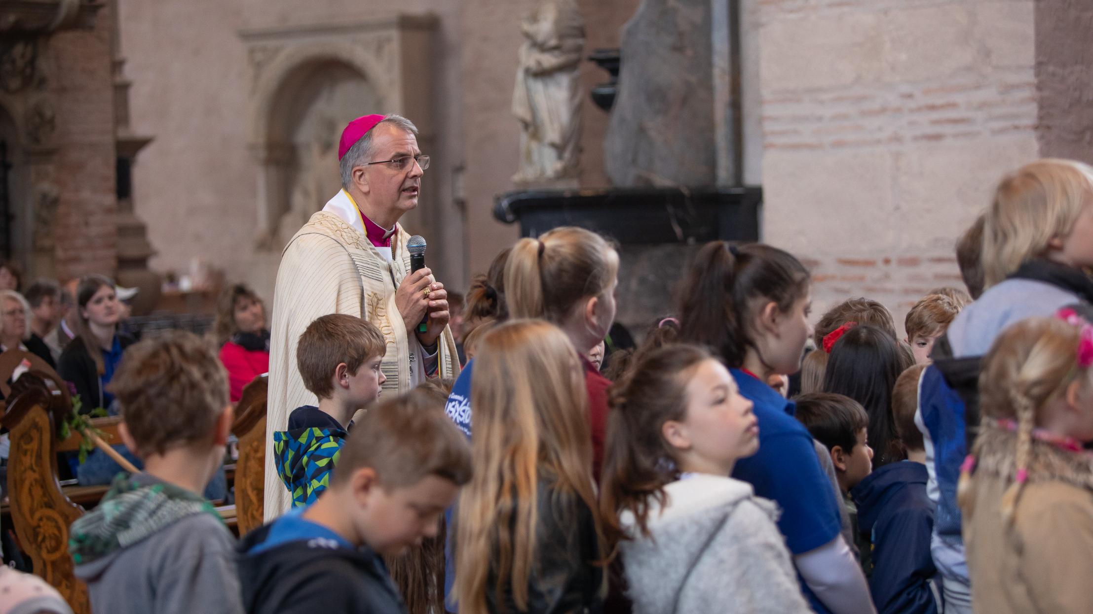 Weihbischof Peters und die Kinder betrachten zusammen das Kreuz.