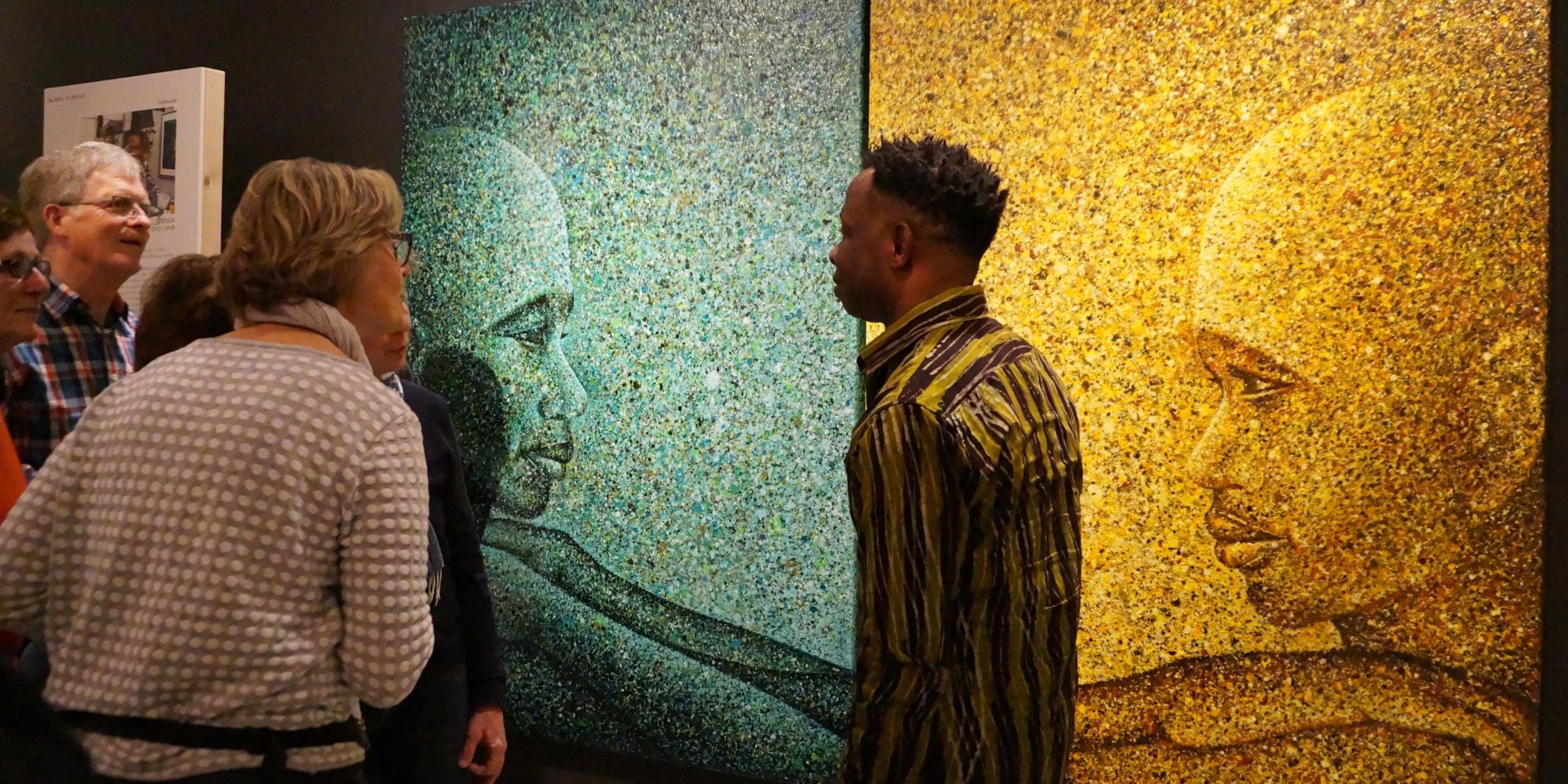 Interessiert folgen Ausstellungsgäste den Erklärungen des nigerianischen Künstlers Chidi Kwubiri über seine „Dripping-Technik“, eine spezielle Farb-Tropf-Technik.