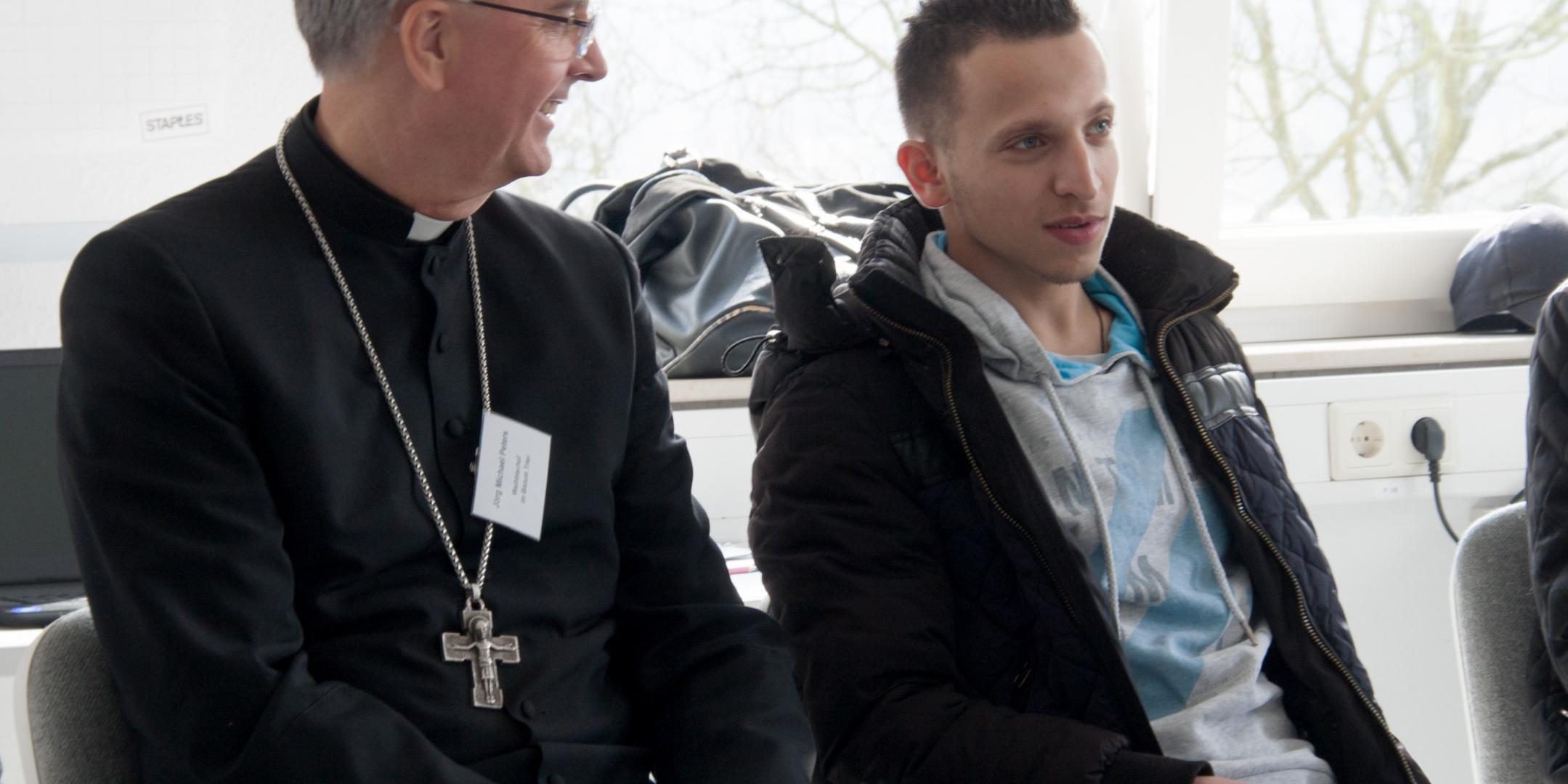 Weihbischof Peters im Gespräch mit einem jungen Mann, der einen Jugendintegrationskurs besucht.