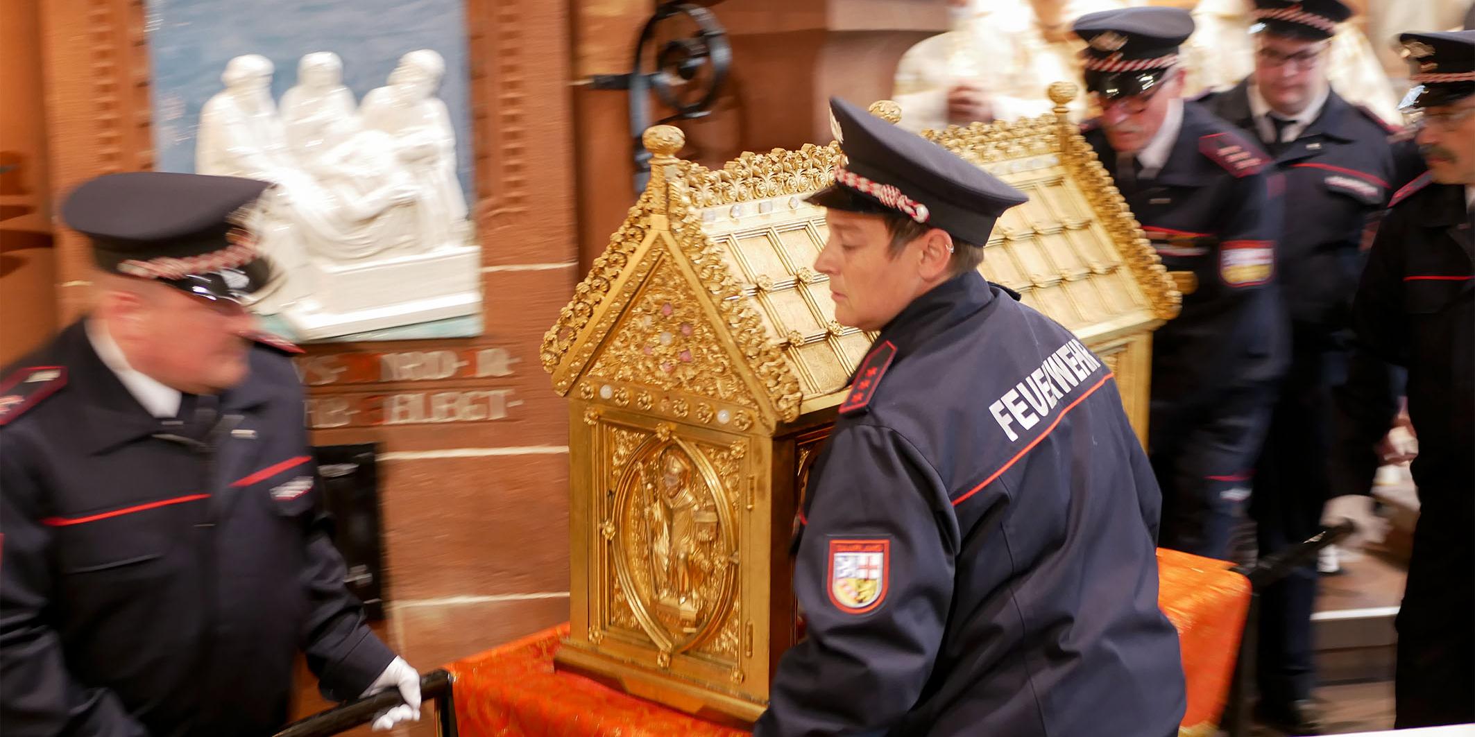 Mitglieder der Freiwilligen Feuerwehr Mettlach tragen den Lutwinusschrein durch die Kirche zum Altar.