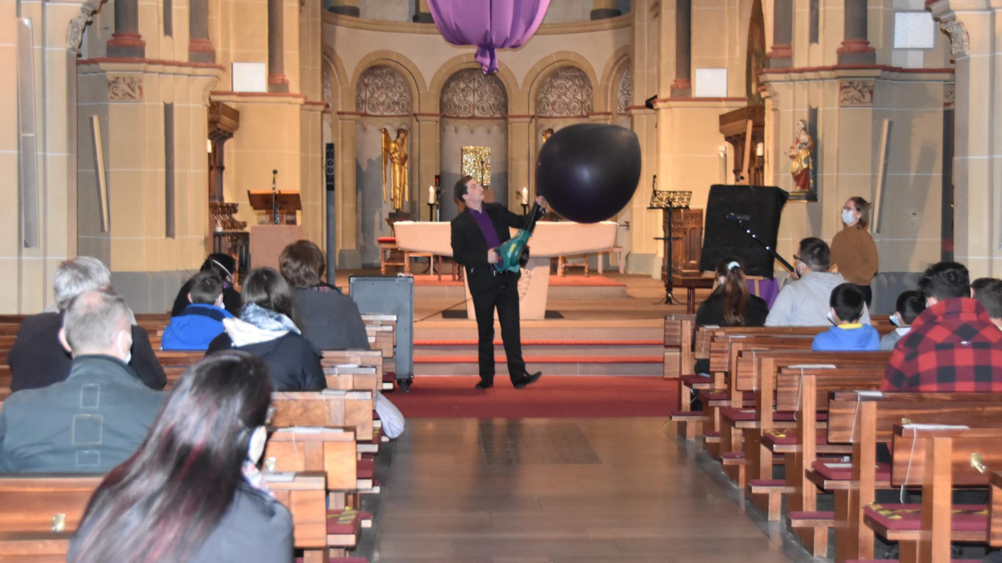 Mit einer Art Laubbläser pustet Maxim Maurice (Philipp Daub) den Ballon im Altarraum auf. Foto: uk