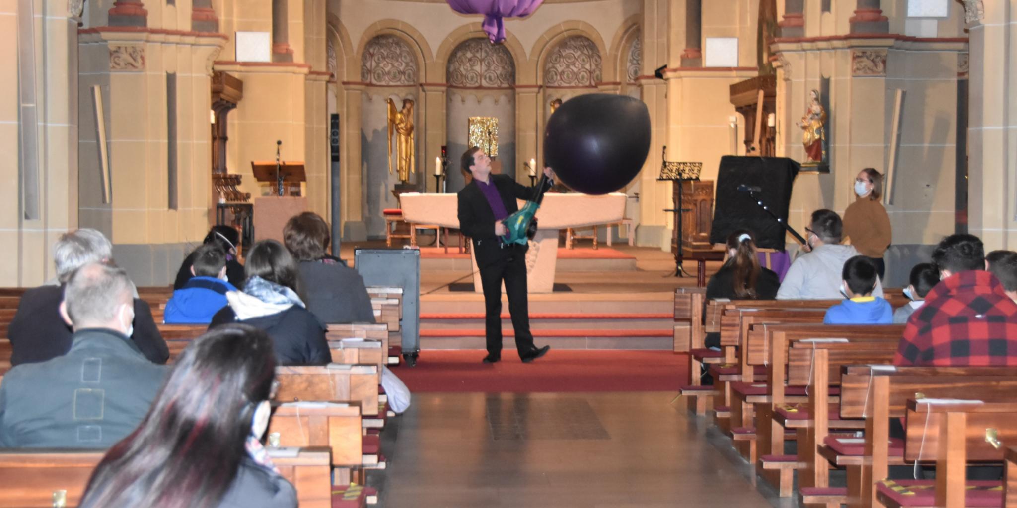 Mit einer Art Laubbläser pustet Maxim Maurice (Philipp Daub) den Ballon im Altarraum auf. Foto: uk