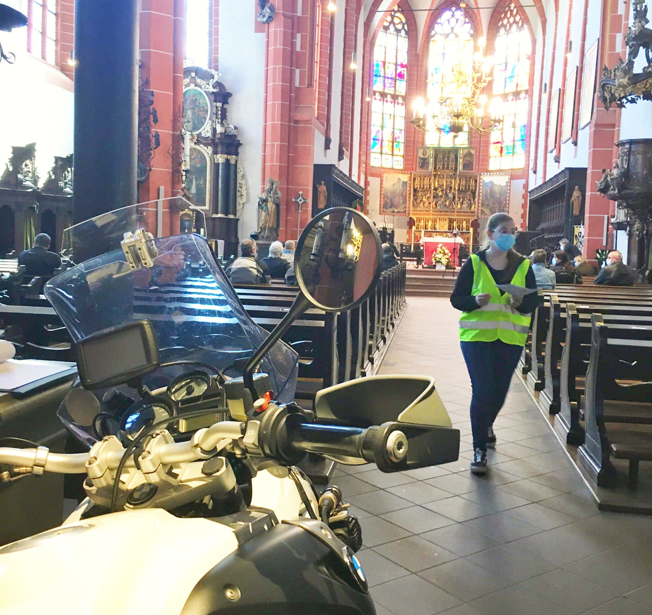 Das Motorrad steht für den Einzug in die Kirche bereit. Die Helferin koordinert die Sitzplatzbelegung.