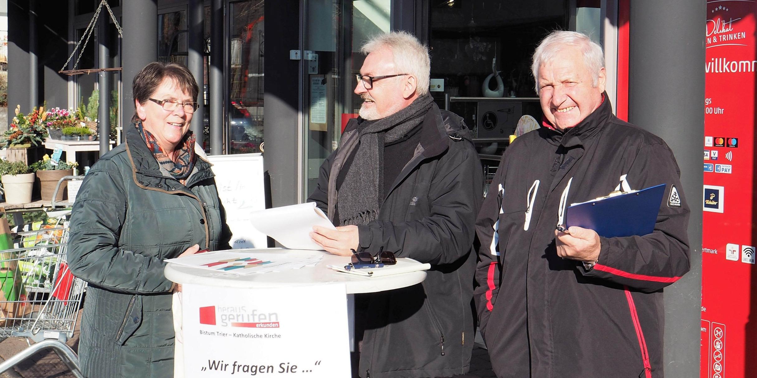 „Sozialraumerkundung“ vor dem Supermarkt: Edith Schug aus Masburg hat für die kurze Befragung durch das Erkundungsteam Herbert Tholl und Karl-Heinz Gilles (von links) ihren Samstags-Einkauf in Kaisersesch unterbrochen.