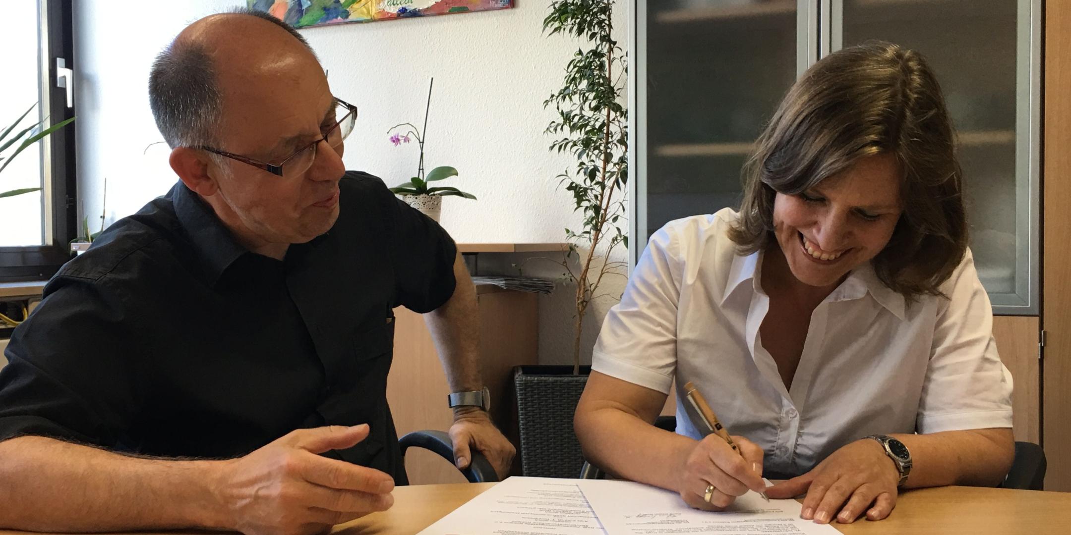 Pfarrer Stephan Wolff und Anja Erhardt beim Unterzeichnen des Kooperationsvertrages