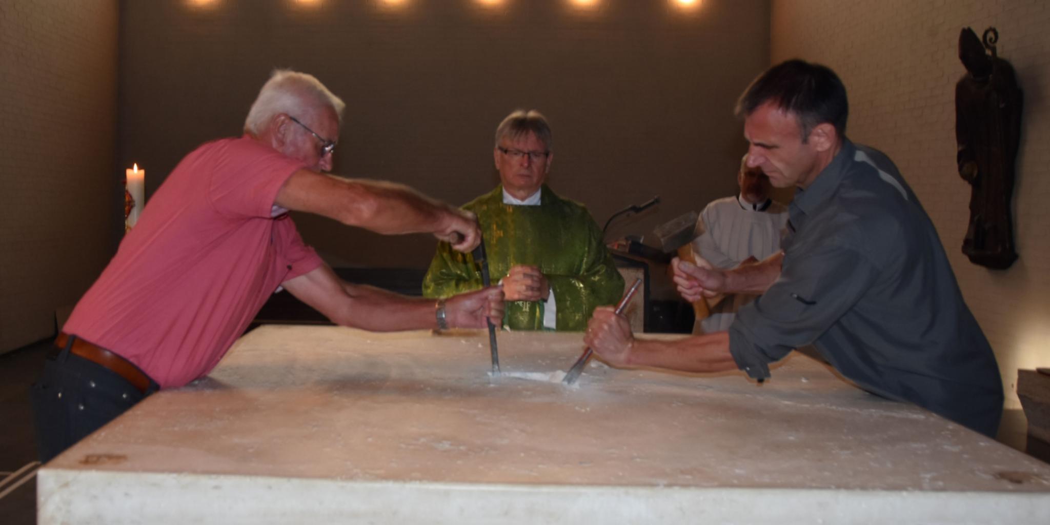 Hausmeister Helmut Sossong (links) und Frank Zeyer (rechts) brechen den Altar auf. Pastor Klaus Leist (Mitte) entnimmt das Reliquiar. Foto: Ute Kirch